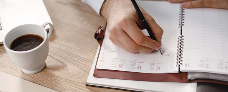 man writing in planner