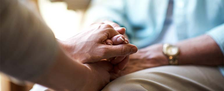 Image of people holding hands during a grief support meeting