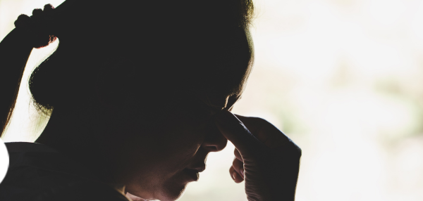Dark silhouette of a woman pinching her eyes in grief